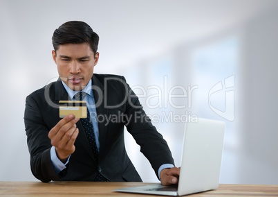 Businessman at desk with laptop with bright background with bankcard