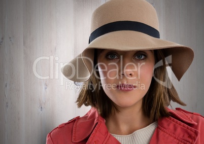 Woman against wood with hat and coat