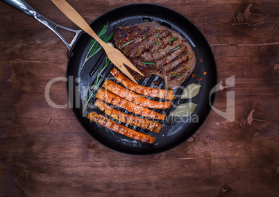 frying pan with a piece of fried beef and carrots