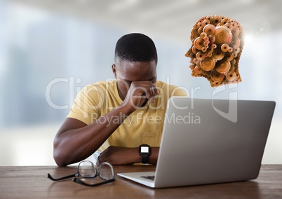 Businessman with laptop at desk with cogs head