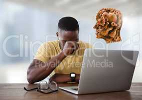 Businessman with laptop at desk with cogs head