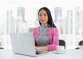 Businesswoman at desk with laptop with bright background