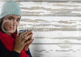 Woman against wood with warm scarf and hat and cup