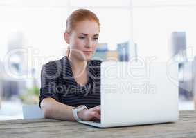 Businesswoman at desk with laptop with bright background