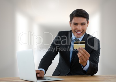 Businessman with laptop at desk with bank card with bright background