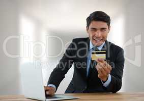 Businessman with laptop at desk with bank card with bright background