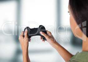 woman playing with computer game controller with bright blurred background