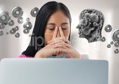 Businesswoman with laptop at desk with cog's head