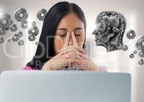 Businesswoman with laptop at desk with cog's head