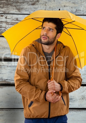 Man against wood with umbrella and coat