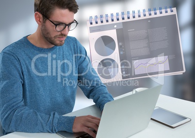 Businessman with laptop at desk with diagrams and charts