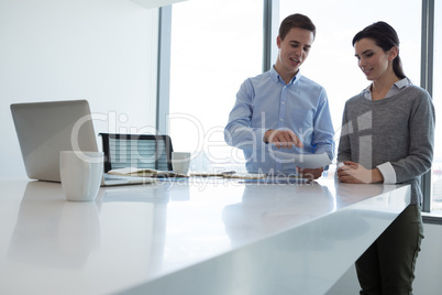 Male executive and female executive discussing over document