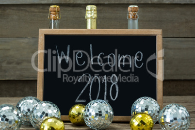 Welcome 2018 written on slate board with baubles and champagne bottle