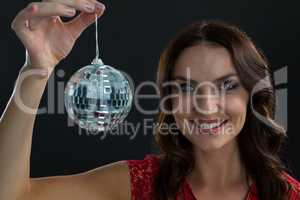 Smiling woman holding mirror ball against black background