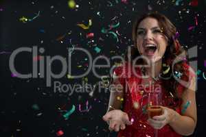 Woman celebrating the New year with falling confetti streamers and champagne