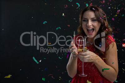 Woman celebrating the New year with falling confetti streamers and champagne