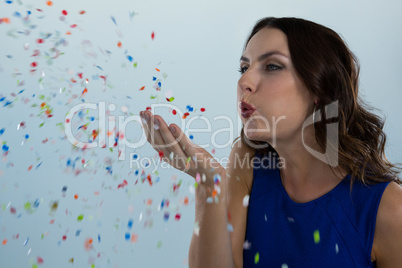 Woman blowing colorful glitter in the air