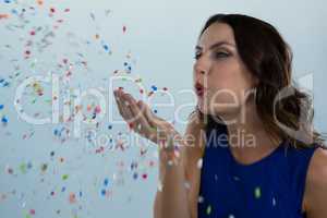 Woman blowing colorful glitter in the air