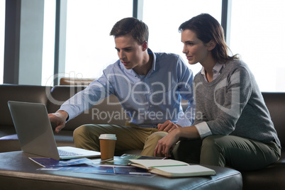 Male executive and female executive discussing over laptop