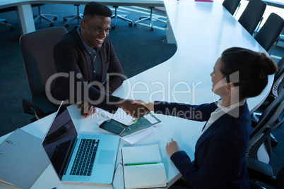 Overhead of executives shaking hands at desk