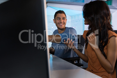 Male and female executive discussing over computer