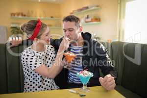 Woman feeding ice cream to man in restaurant