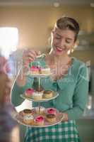Waitress holding tray of muffins in restaurant