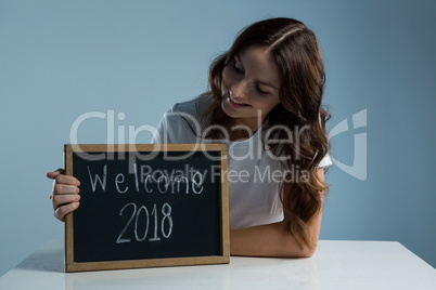Smiling woman showing slate with text welcome 2018