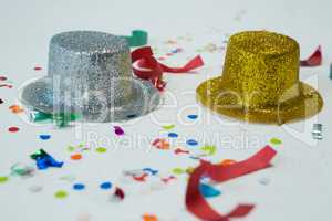 Golden and silver hat with confetti on white background