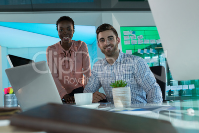 Portrait of smiling executives working together at desk