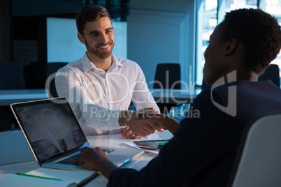 Executives shaking hands at desk