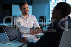 Executives shaking hands at desk