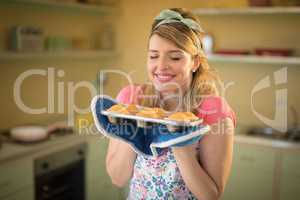 Woman holding tray of muffins in restaurant