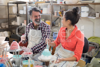 Happy male and female potter painting bowl