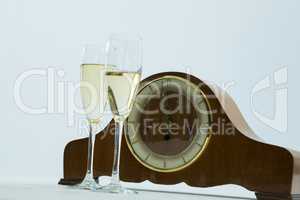 Champagne glass and clock on white background