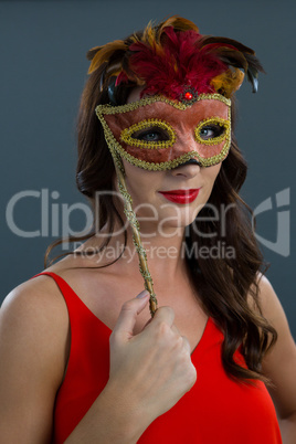 Woman wearing masquerade mask against black background