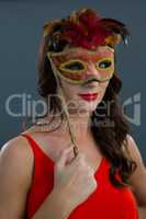 Woman wearing masquerade mask against black background