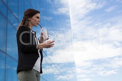 Female executive using glass sheet while having milkshake