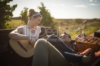 Woman playing guitar while man listening in a car