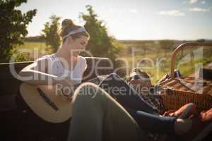 Woman playing guitar while man listening in a car