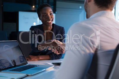 Executives shaking hands at desk