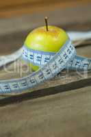 Green apple with measuring tape on wooden table