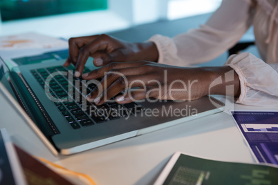 Female executive using laptop at desk in futuristic office