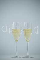 Two champagne flutes against white background