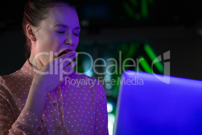 Female executive yawing while using laptop