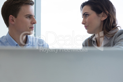 Male executive and female executive working over laptop