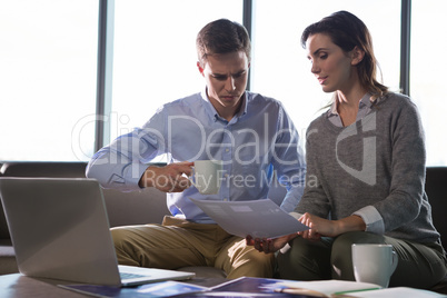 Male executive and female executive discussing over document