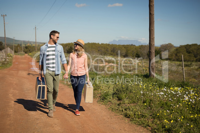 Couple walking with their luggage on a sunny day