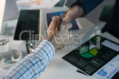 Executives shaking hands at desk