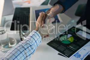 Executives shaking hands at desk